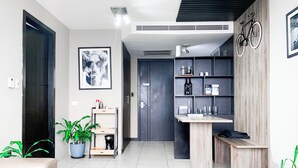 A modern living room with a sofa, a coffee table, a bookshelf, and a dining area.