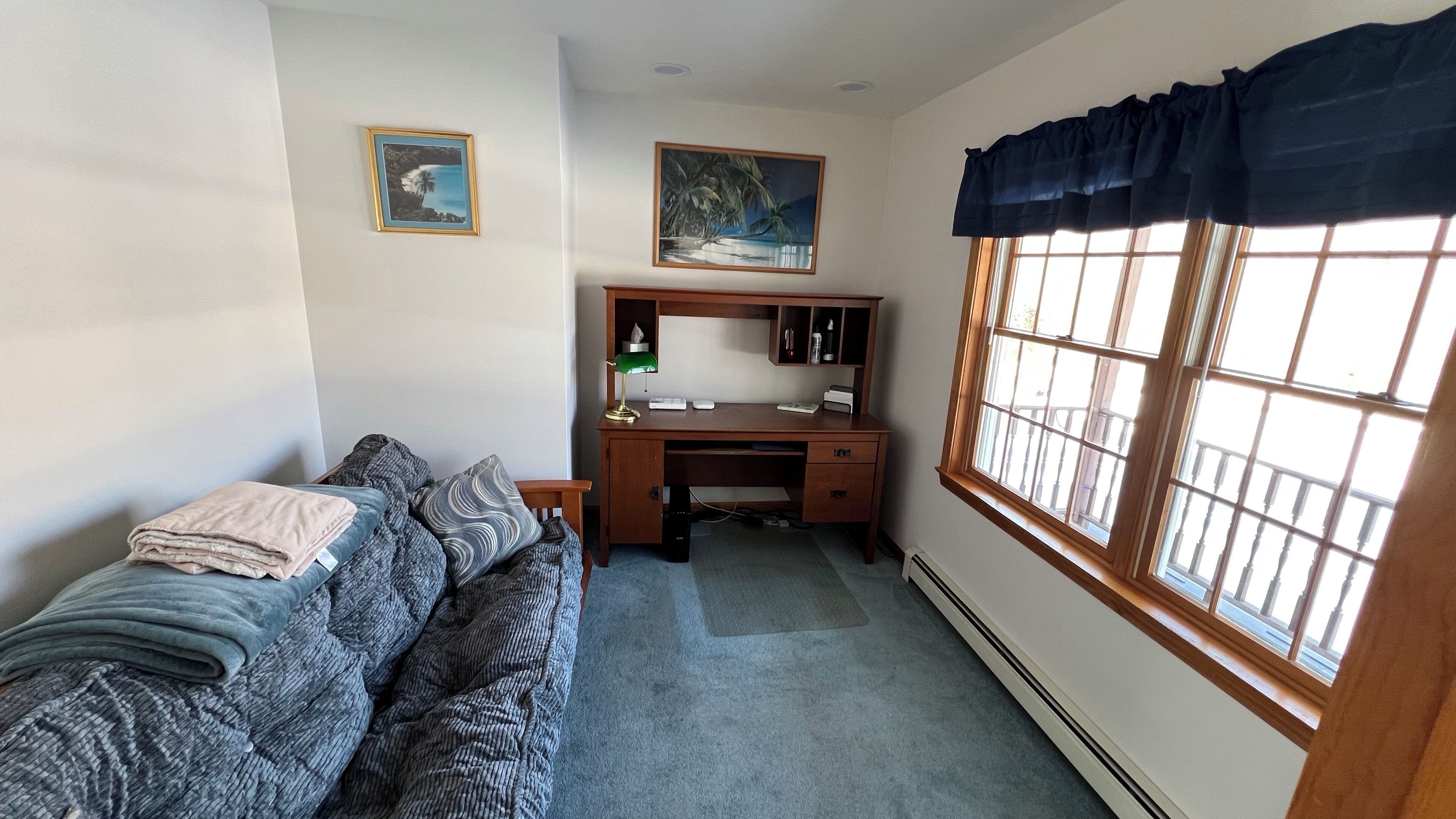 Ein Schlafzimmer mit einem Bett, einem Schreibtisch und einem Fenster.