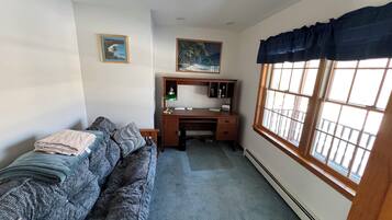 Een slaapkamer met een bed, een bureau en een raam.