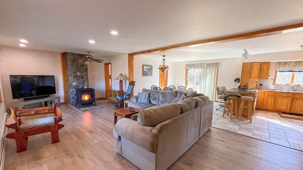 A spacious living room with a large sectional sofa, a television, a fireplace, and a dining area with bar stools. - Hiking,canoeing,fishing,close to atv,utv trails (Madrid)