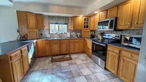A kitchen with wooden cabinets, a stainless steel sink, a microwave, and an oven. - Hiking,canoeing,fishing,close to atv,utv trails (Madrid)