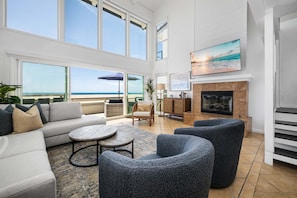 A spacious living area with a sofa, round tables, and a fireplace.
