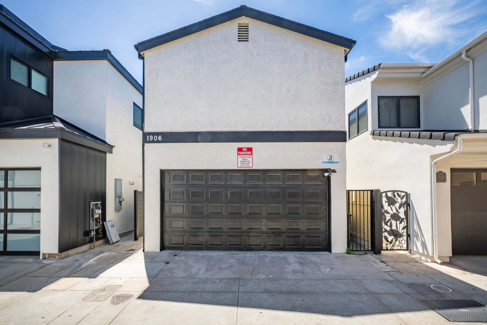 A residential building with a garage door, a 'NO PARKING' sign, and a mailbox.