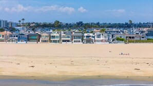 A beachfront hotel with modern architecture, a sandy beach, and a clear view of the ocean. - Spacious Oceanfront Home Near Newport Pier (Newport Beach)