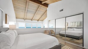 A bedroom with a large bed, a wardrobe, a chair, and a view of the sea. - Spacious Oceanfront Home Near Newport Pier (Newport Beach)