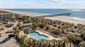Un complexe hôtelier doté d’une piscine, d’un accès à la plage et d’une jetée qui s’avance dans l’océan.
