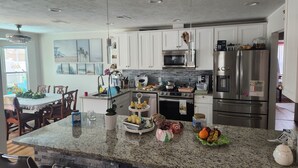 A modern kitchen with granite countertops, stainless steel appliances, and a dining area with a table and chairs. - 3-bedroom house in marvelous New Port Richey with WiFi, AC (New Port Richey)