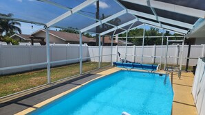 A swimming pool with a covered area and a white fence in the background. - 3-bedroom house in marvelous New Port Richey with WiFi, AC (New Port Richey)