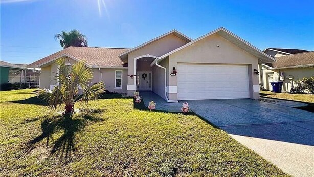 A single-story house with a garage, a front porch, and a small lawn with a palm tree. - 3-bedroom house in marvelous New Port Richey with WiFi, AC (New Port Richey)