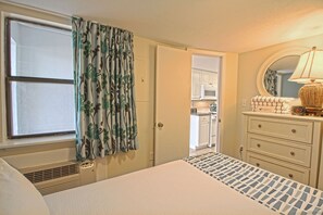 Une chambre à coucher avec un lit, une commode, un miroir et une fenêtre avec des rideaux.