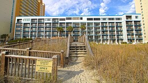 Ein mehrstöckiges Hotel mit Zugang zum Strand, einem Schild, das privates Eigentum kennzeichnet, und freiem Blick auf das Meer.