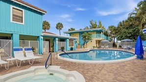 A pool area with a hot tub, lounge chairs, and a building with a blue exterior. - 1-Bedroom Rental w/ Ocean Views (Palm Beach Shores)