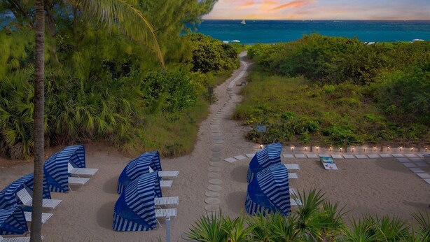 A beach pathway leading to a seating area with umbrellas and chairs, overlooking the ocean. - Beachfront Studio w/ Ocean Views (Palm Beach Shores)