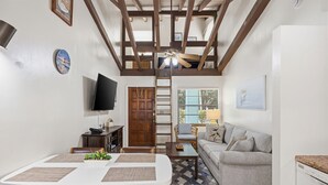 A compact living space with a dining area, a sofa, a TV, and a ceiling fan.