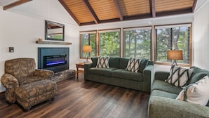 A living room with a fireplace, two sofas, a patterned armchair, and large windows with blinds. - Scenic Getaway in Jasper Mountains (Marble Hill)