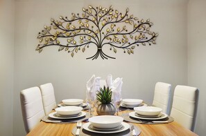 A dining table set with white plates, silverware, and a centerpiece of a pineapple.