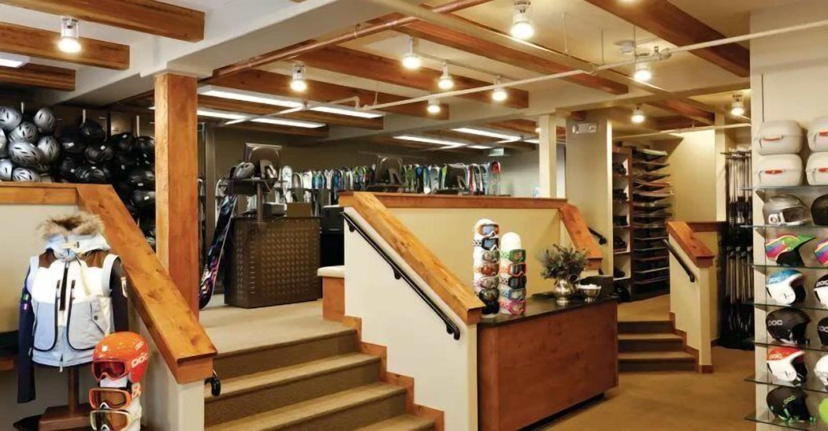 A store with a wooden staircase, shelves with helmets, and a display of ski gear.