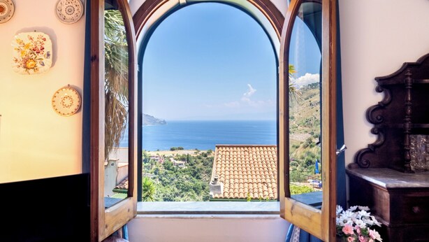A room with a large arched window offering a view of the sea and a hillside. - Villa Valmar - Villa with a view (Taormina)