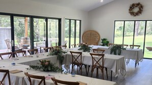 A spacious room with large windows, wooden flooring, and tables set for a gathering. - Urban Connection Farm (Eagleton)