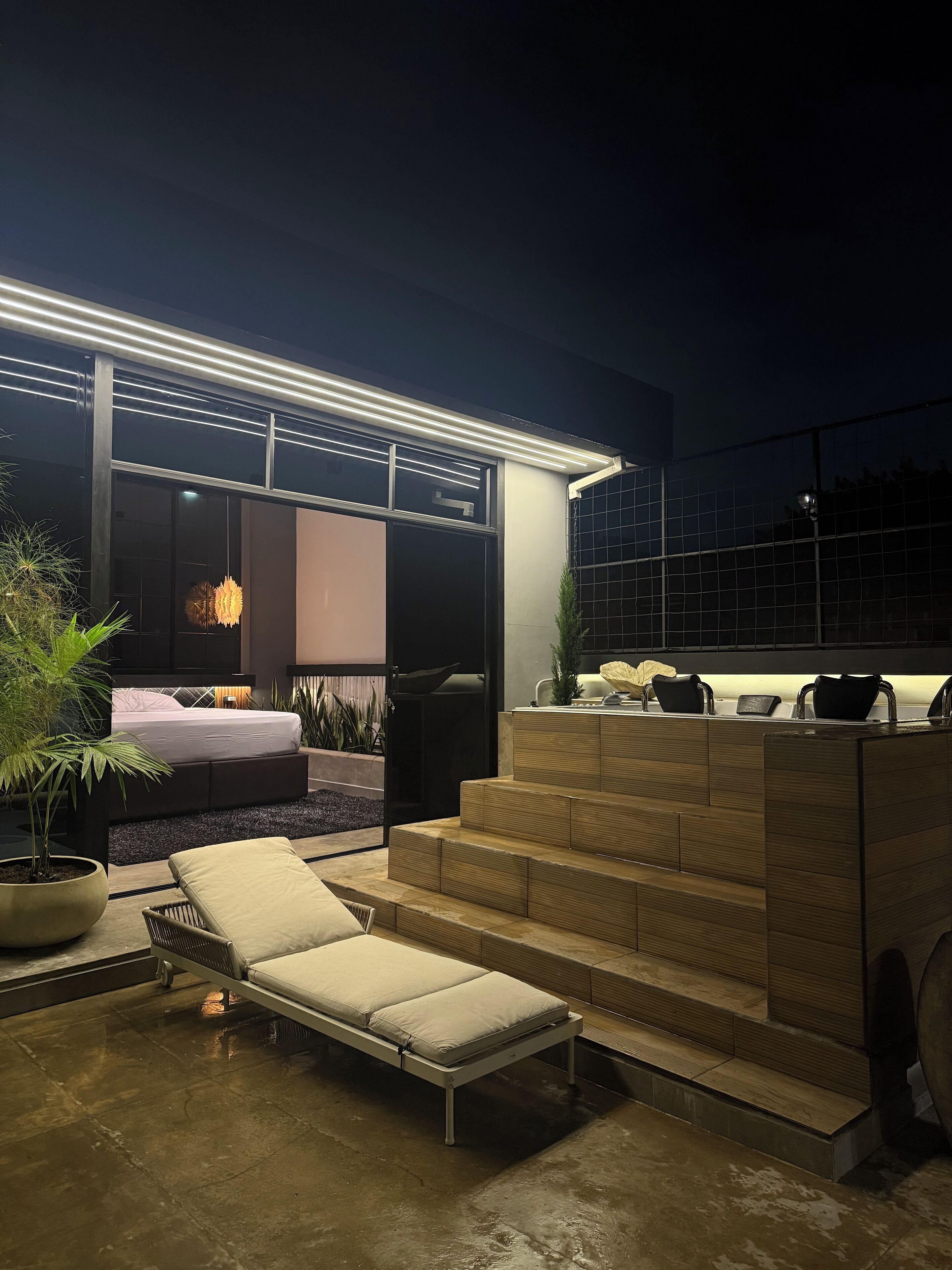 A modern outdoor living space with a sofa, a lounge chair, and a staircase leading to an upper level.