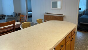 Una cocina compacta con una isla central, armarios de madera y un comedor con sillas.