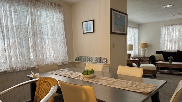 Un comedor con una mesa, sillas, un tazón de fruta y un cartel que dice 'Let's Do Sunset'.