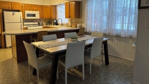 Una cocina con armarios de madera, microondas, estufa y comedor con mesa y sillas.