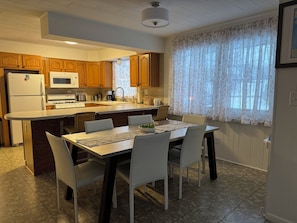 A kitchen with wooden cabinets, a microwave, a stove, and a dining area with a table and chairs.