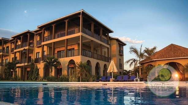 Un hotel de varios pisos con balcones, piscina y palmeras.