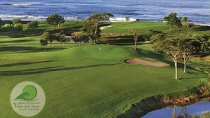 Campo de golf con un cuerpo de agua y árboles, y un logotipo que indica un resort de playa y golf.