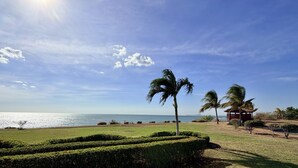 Paisaje costero con cielo despejado, palmeras y una pequeña construcción.