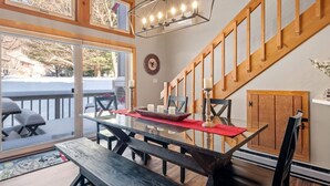 A dining area with a glass table, benches, and a wooden staircase.
