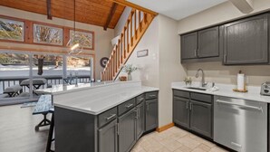 A modern kitchen with dark cabinets, a stainless steel refrigerator, and a large island.