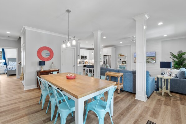 A modern kitchen with white cabinets, a wooden dining table, and blue chairs. - "Blutopia" - 4 Bedroom, 3.5 Bathroom Oak Island Home (Oak Island)