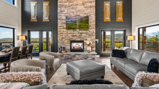 A spacious living room with a stone fireplace, leather sofas, and a view of the outdoors.