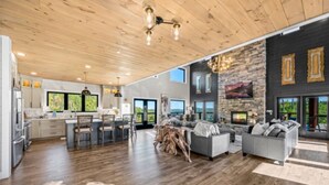 A spacious living area with a fireplace, wooden flooring, and a large window.