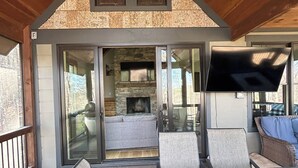 Un patio al aire libre con chimenea de piedra, asientos y una pantalla de televisión.