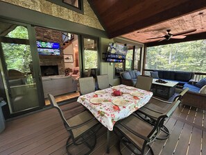 Une terrasse extérieure avec une table à manger pour quatre personnes, entourée de chaises.