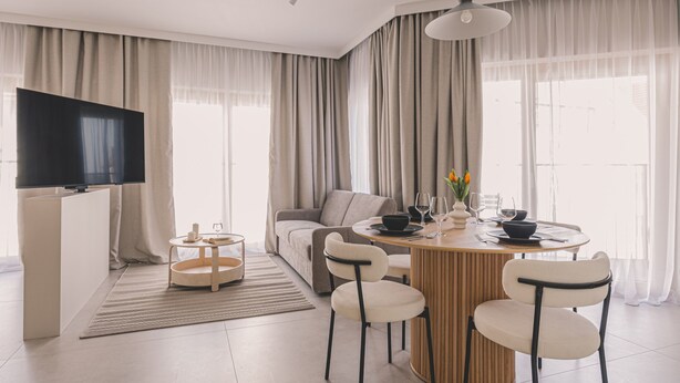 A modern living room with a flat-screen TV, a round dining table, and a sofa. - Casa Przestronne Studio z Balkonem Klimatyzacja Opera Nova Star wka (Bydgoszcz)