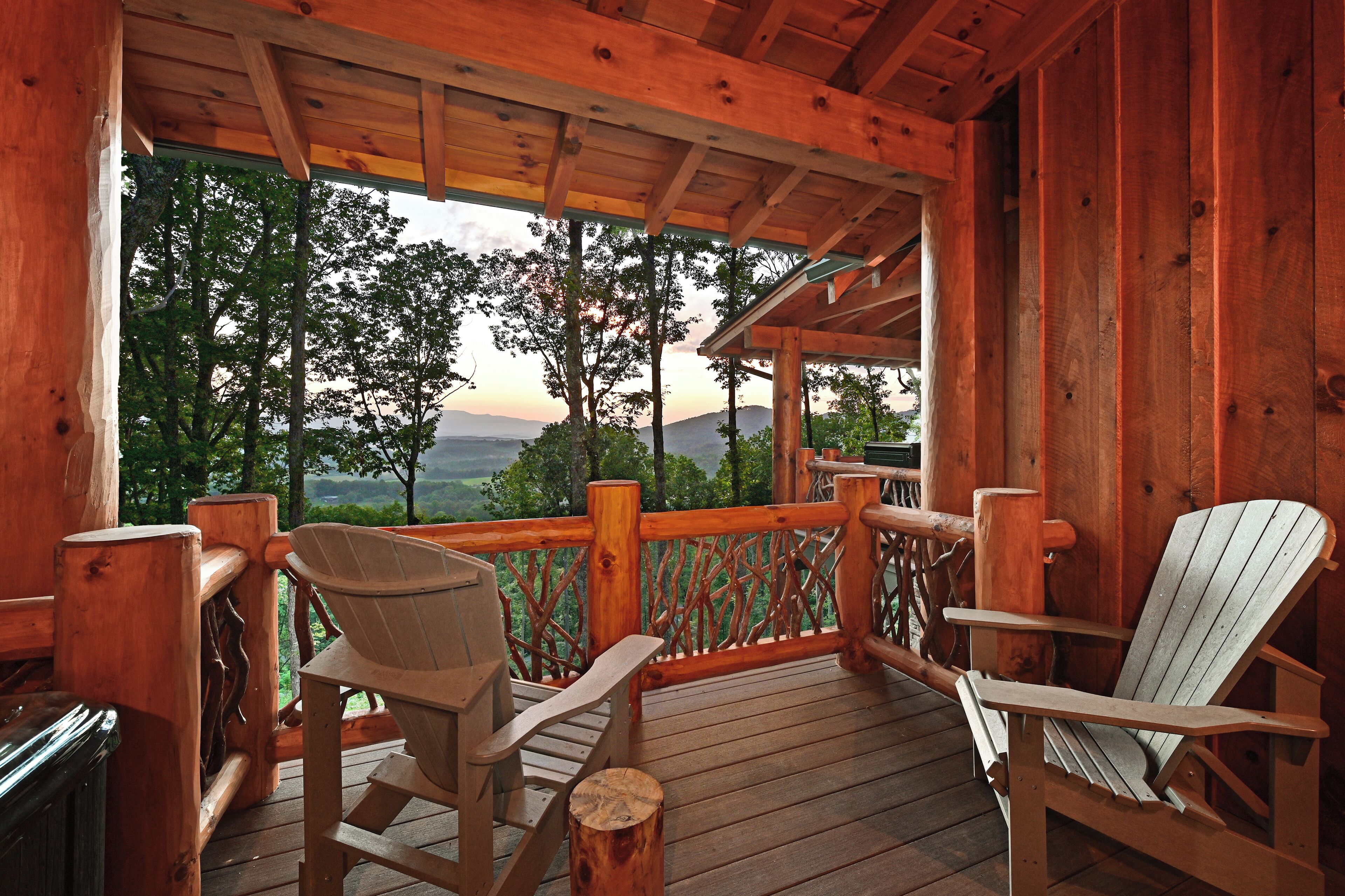 A wooden deck with Adirondack chairs and a view of a mountainous landscape.
