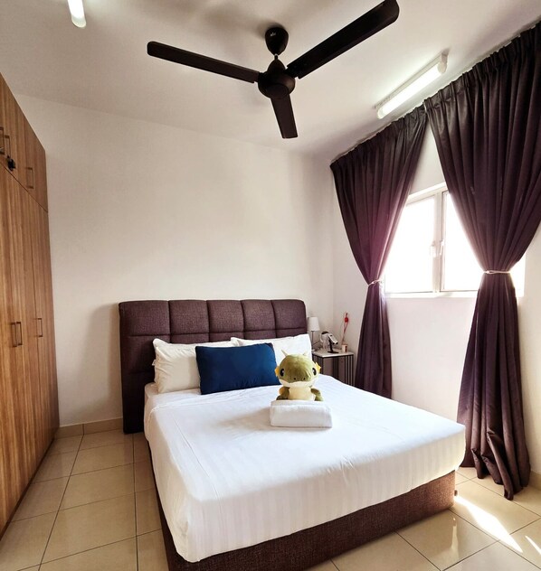 A hotel room with a bed, a ceiling fan, a window with curtains, and a wooden wardrobe. - Comfy Alanis Sepang KLIA Airport 1R1B (Sepang)