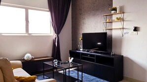 Un salon moderne avec un canapé, une table basse, un téléviseur et un ventilateur de plafond.