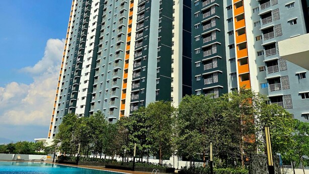 Un immeuble résidentiel de grande hauteur, doté de nombreux balcons, d’une piscine et d’une végétation luxuriante au premier plan.