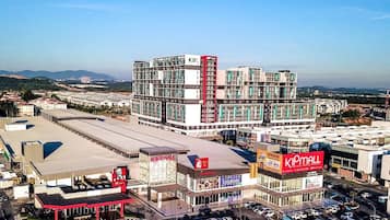 Zona comercial con una destacada tienda KIPMALL, una gasolinera y un edificio grande de varios pisos con detalles en rojo.
