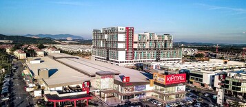 A commercial area with a prominent KIPMALL store, a gas station, and a large building with multiple floors and a red accent.