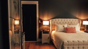 Un dormitorio con una cama grande, dos mesitas de noche con lámparas, un espejo y una puerta.
