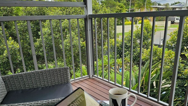 A balcony with a table, a chair, a smartphone, a mug, and a sign.