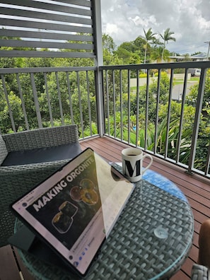 A balcony with a table, a chair, a smartphone, a mug, and a sign. - 3 Bedroom Townhouse in Kallangur (Kallangur)