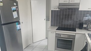 A modern kitchen with a stainless steel refrigerator, a built-in oven, and a black tiled backsplash.