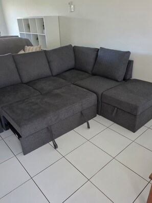 A sectional sofa with a footrest and a side table in a room with white tiled flooring. - 3 Bedroom Townhouse in Kallangur (Kallangur)
